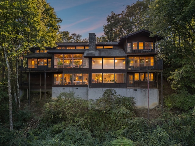 back house at dusk featuring a balcony