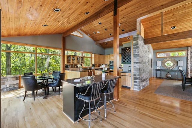 kitchen featuring high vaulted ceiling, light hardwood / wood-style flooring, wooden ceiling, and a breakfast bar