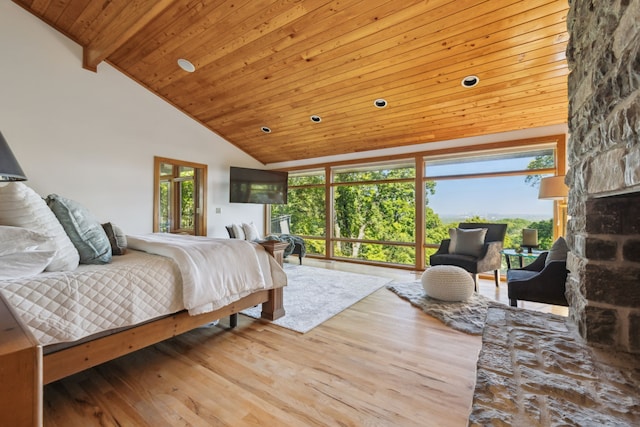 bedroom featuring a stone fireplace, wood ceiling, high vaulted ceiling, beam ceiling, and light hardwood / wood-style floors