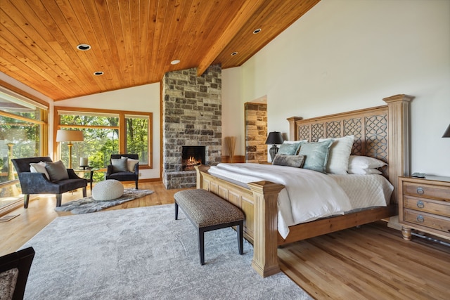 bedroom featuring hardwood / wood-style flooring, a stone fireplace, high vaulted ceiling, and wooden ceiling