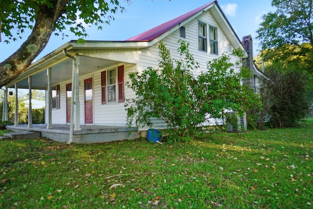 view of side of property with a lawn and covered porch