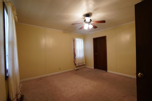 empty room featuring crown molding, carpet flooring, and ceiling fan