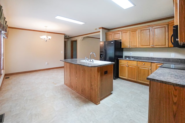 kitchen featuring pendant lighting, black appliances, crown molding, a center island with sink, and an inviting chandelier