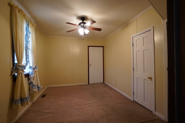 empty room with ornamental molding, light colored carpet, and ceiling fan