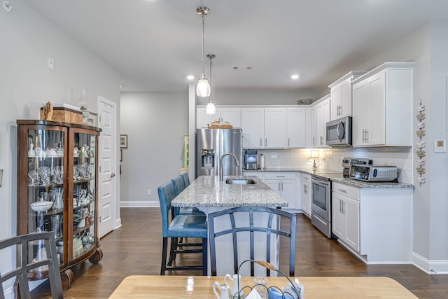 kitchen featuring light stone countertops, appliances with stainless steel finishes, white cabinets, and dark hardwood / wood-style flooring