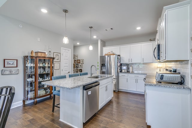 kitchen with dark hardwood / wood-style floors, a kitchen island with sink, sink, and white cabinetry