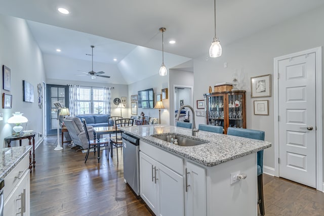 kitchen with a center island with sink, sink, hanging light fixtures, stainless steel dishwasher, and white cabinetry