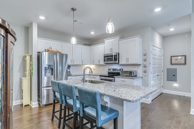 kitchen featuring dark hardwood / wood-style floors, stainless steel appliances, hanging light fixtures, a kitchen bar, and white cabinetry