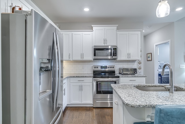 kitchen featuring white cabinets, stainless steel appliances, pendant lighting, and dark hardwood / wood-style flooring