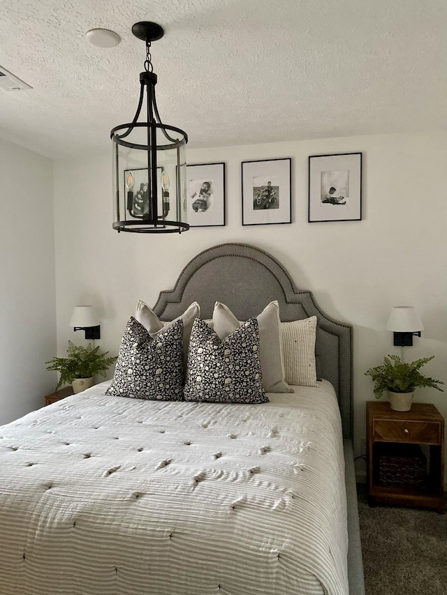 carpeted bedroom with an inviting chandelier and a textured ceiling