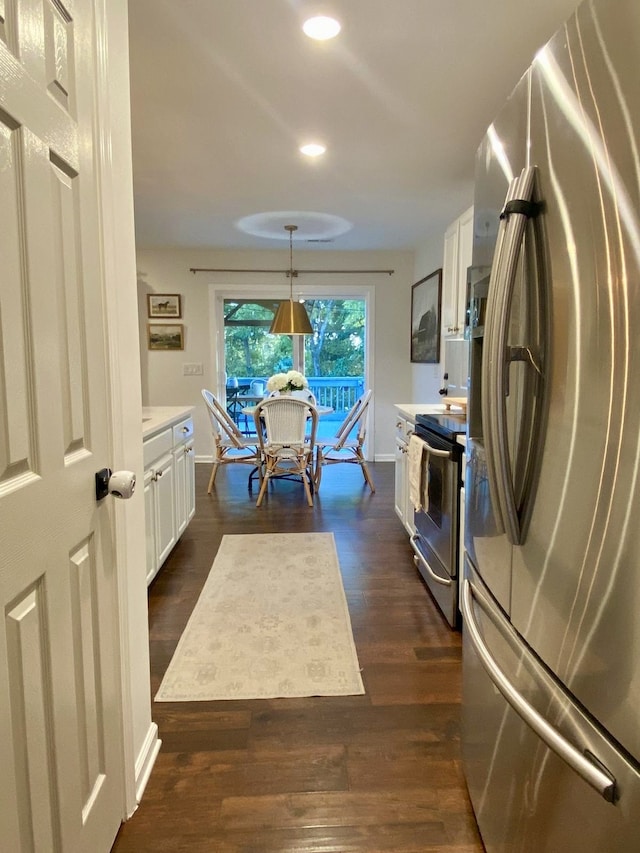 kitchen featuring dark hardwood / wood-style flooring, white cabinetry, appliances with stainless steel finishes, and hanging light fixtures