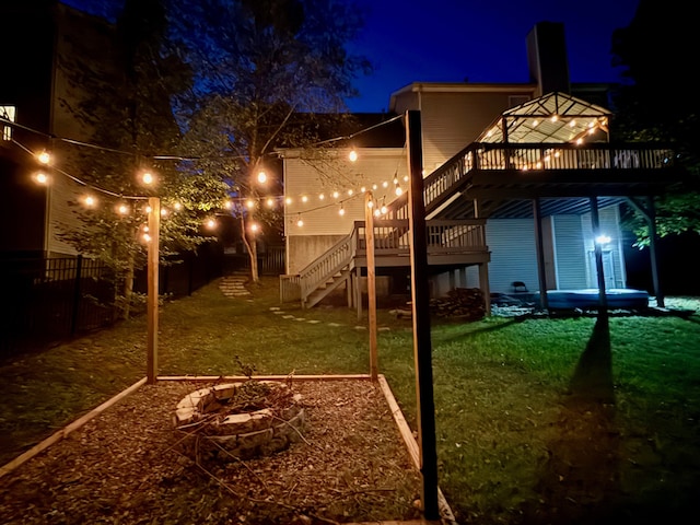 back house at night featuring a deck, a yard, and an outdoor fire pit