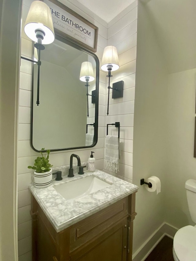 bathroom featuring vanity, toilet, and lofted ceiling