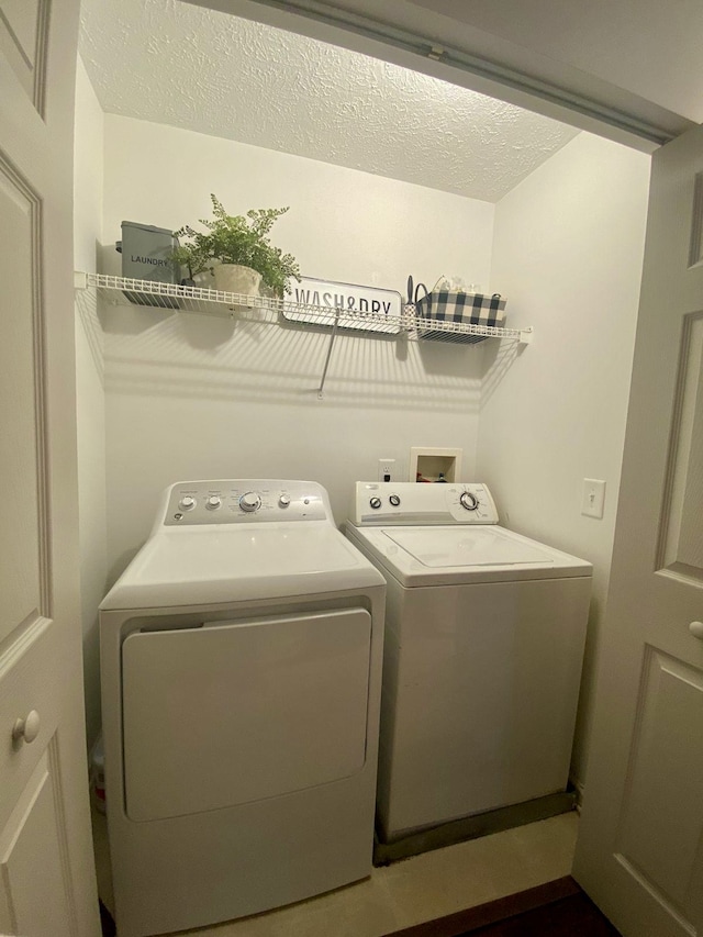 clothes washing area featuring a textured ceiling and washer and dryer