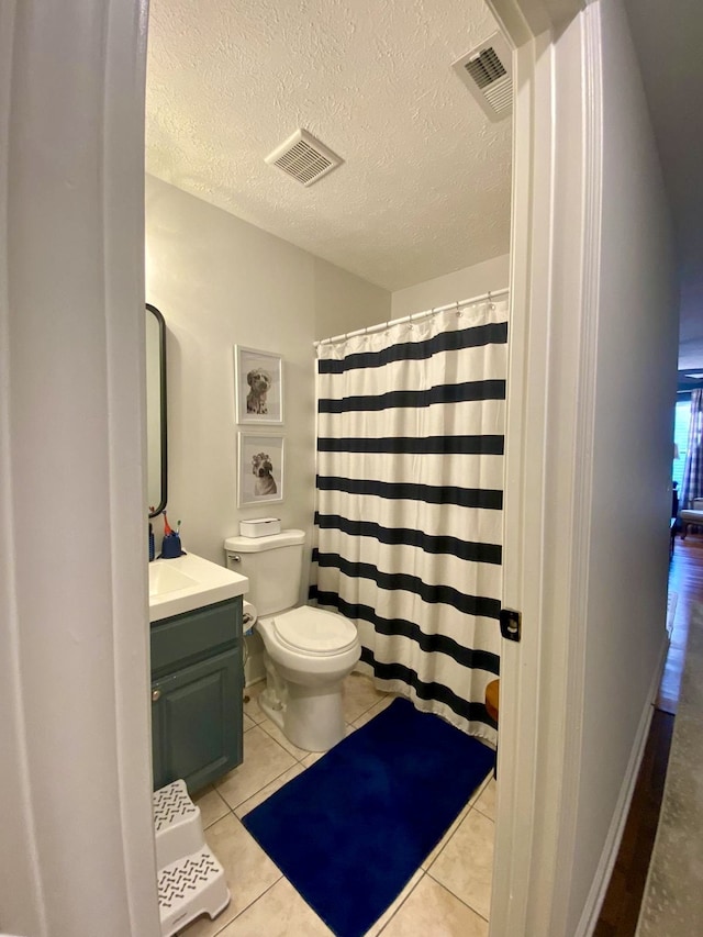 bathroom with tile patterned flooring, vanity, a textured ceiling, and toilet