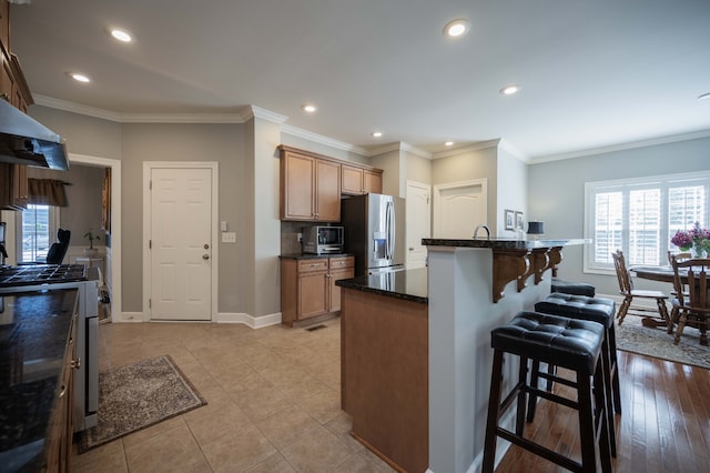 kitchen featuring appliances with stainless steel finishes, crown molding, a breakfast bar area, and light hardwood / wood-style floors