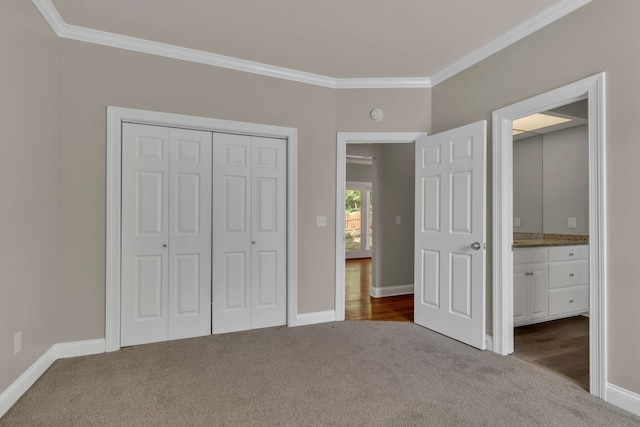 unfurnished bedroom with carpet floors, a closet, ornamental molding, and ensuite bath