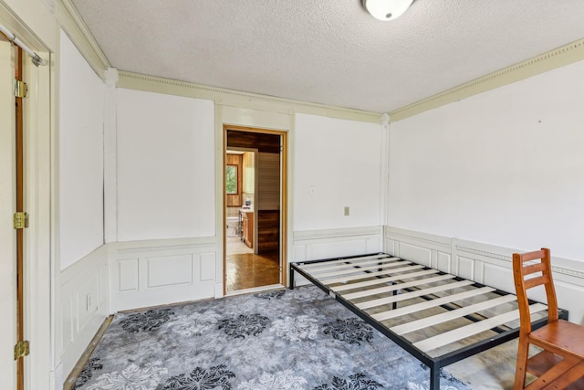 unfurnished bedroom with carpet floors, a textured ceiling, wainscoting, and a decorative wall