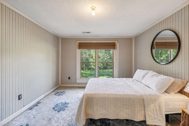bedroom featuring crown molding, visible vents, and wallpapered walls