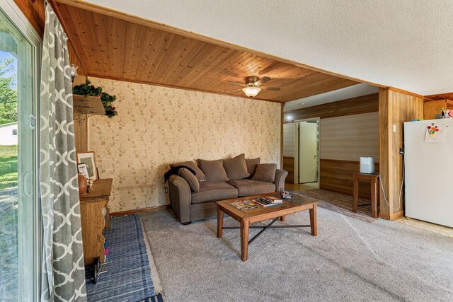 living room featuring carpet flooring, wooden walls, and a ceiling fan