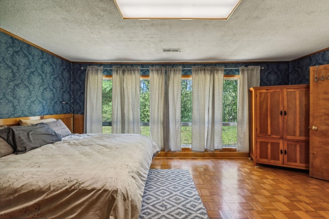 bedroom featuring wallpapered walls, a textured ceiling, and visible vents