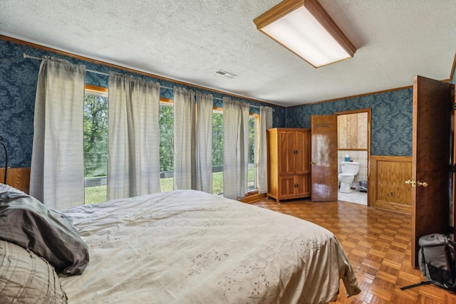 bedroom featuring visible vents, wainscoting, multiple windows, and wallpapered walls