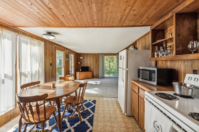 kitchen featuring wooden walls, brown cabinets, crown molding, and white appliances