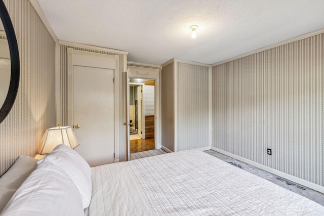bedroom featuring baseboards, wallpapered walls, and a textured ceiling
