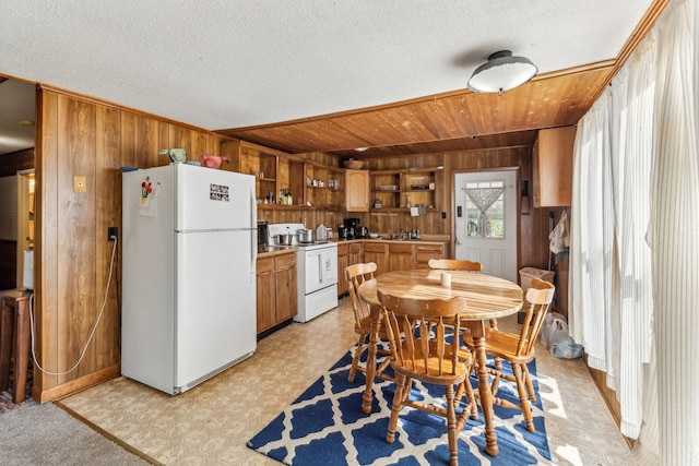 kitchen featuring brown cabinetry, open shelves, white appliances, light floors, and wooden walls