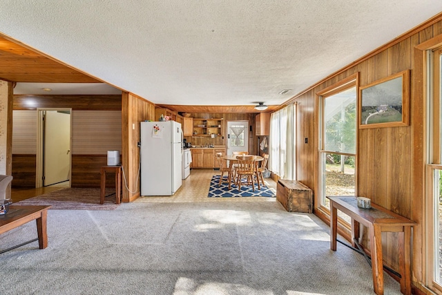 living room featuring wooden walls, a textured ceiling, light carpet, and crown molding