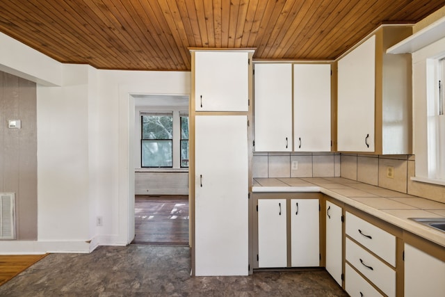 kitchen with dark wood-type flooring, decorative backsplash, wooden ceiling, and white cabinets