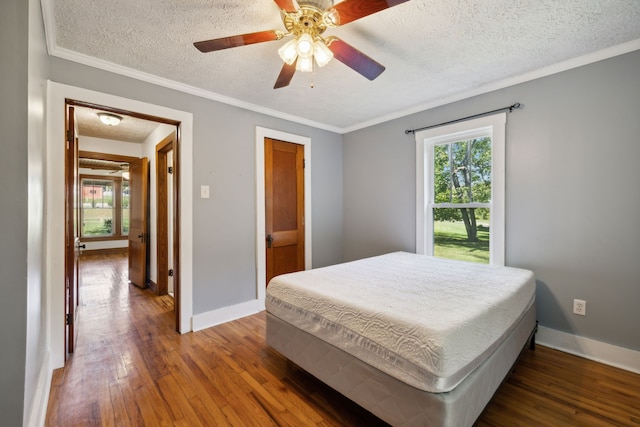 bedroom with dark hardwood / wood-style floors, ornamental molding, a textured ceiling, and ceiling fan