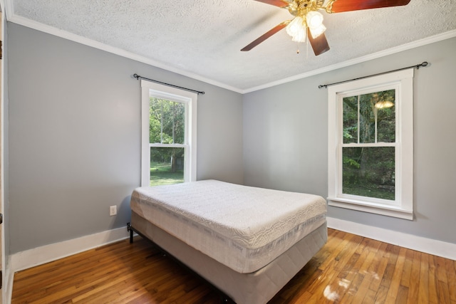 bedroom featuring wood-type flooring, a textured ceiling, ornamental molding, and ceiling fan