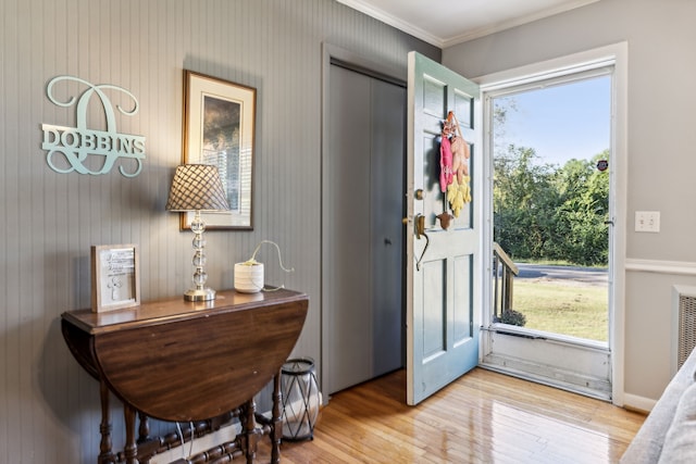 doorway with crown molding and light hardwood / wood-style floors