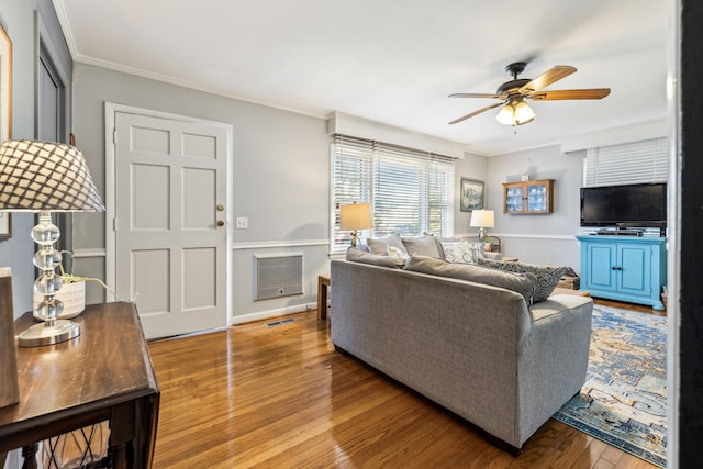 living room with hardwood / wood-style flooring, crown molding, ceiling fan, and heating unit