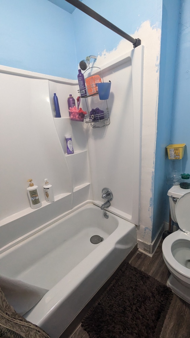 bathroom with toilet, hardwood / wood-style floors, and washtub / shower combination