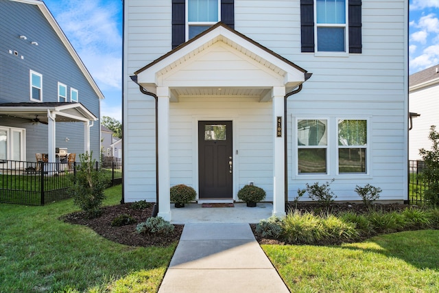 property entrance featuring a lawn and ceiling fan