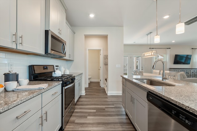 kitchen featuring light stone counters, decorative light fixtures, appliances with stainless steel finishes, and sink