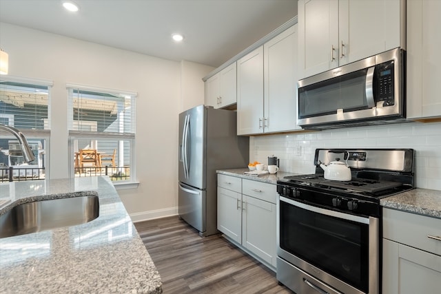 kitchen featuring dark wood-type flooring, backsplash, appliances with stainless steel finishes, and sink