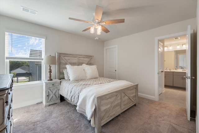 bedroom with ceiling fan, light colored carpet, connected bathroom, and multiple windows