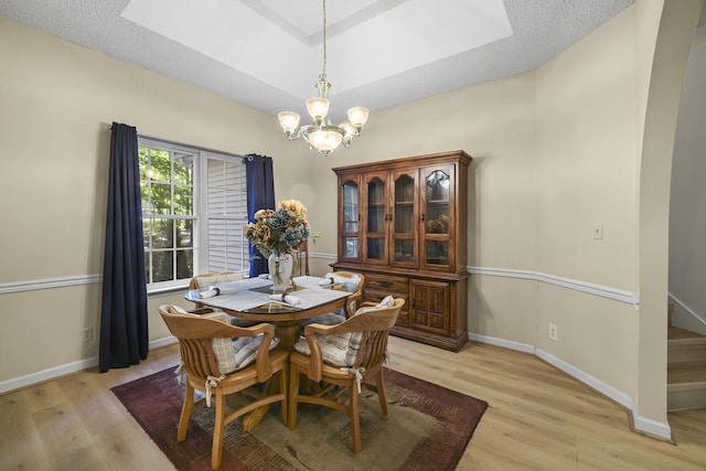 dining space with a textured ceiling, a chandelier, and light hardwood / wood-style floors