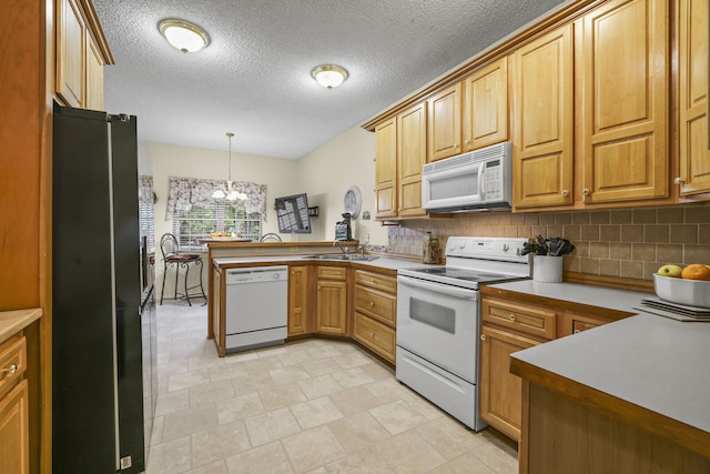 kitchen featuring white appliances, kitchen peninsula, a notable chandelier, decorative light fixtures, and backsplash