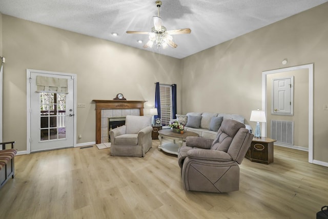 455 Bluff View Dr, Spencer, TN 38585 - living room featuring ceiling fan, light wood-style flooring, baseboards, a tiled fireplace, and a textured ceiling