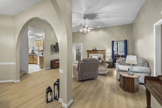 living room with light hardwood / wood-style flooring, a textured ceiling, and ceiling fan