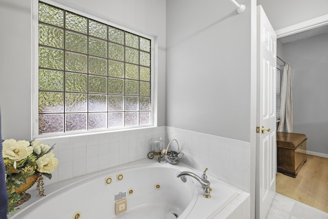 bathroom with tiled bath, plenty of natural light, and hardwood / wood-style floors