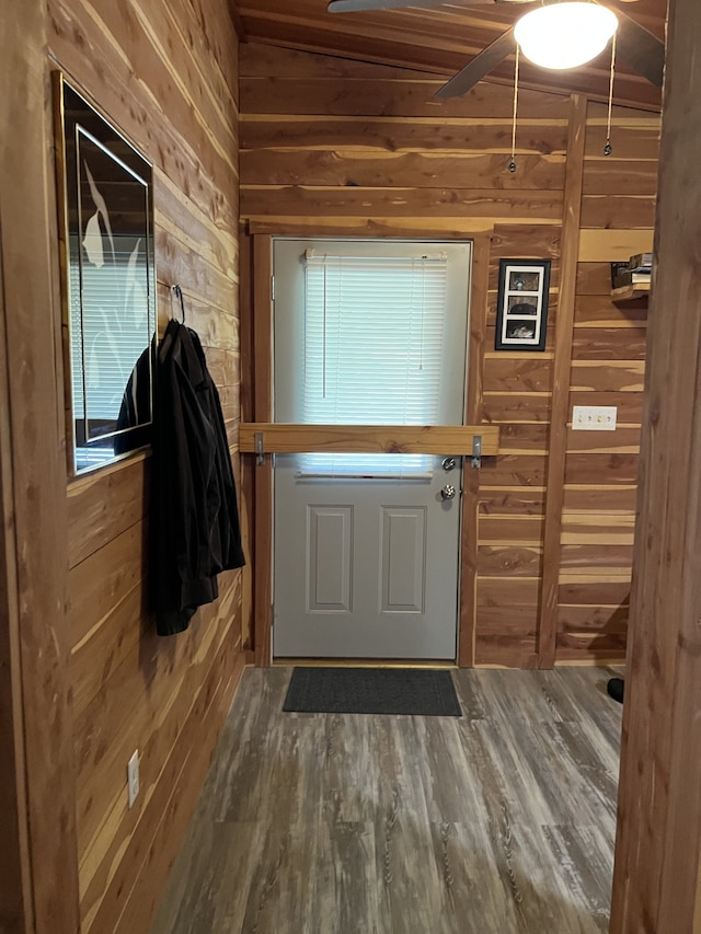 doorway to outside with hardwood / wood-style floors, wooden walls, and ceiling fan