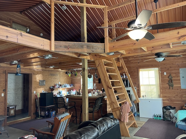 living room with ceiling fan, wood walls, and vaulted ceiling