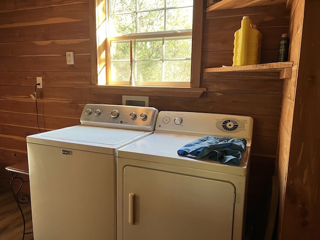 clothes washing area with wood walls and washing machine and clothes dryer