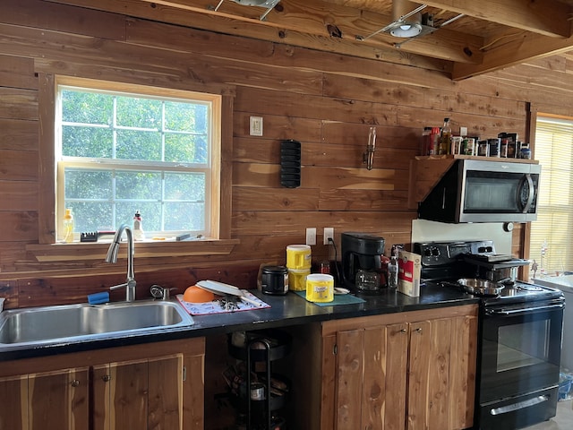 kitchen with black range with electric cooktop, plenty of natural light, wood walls, and sink