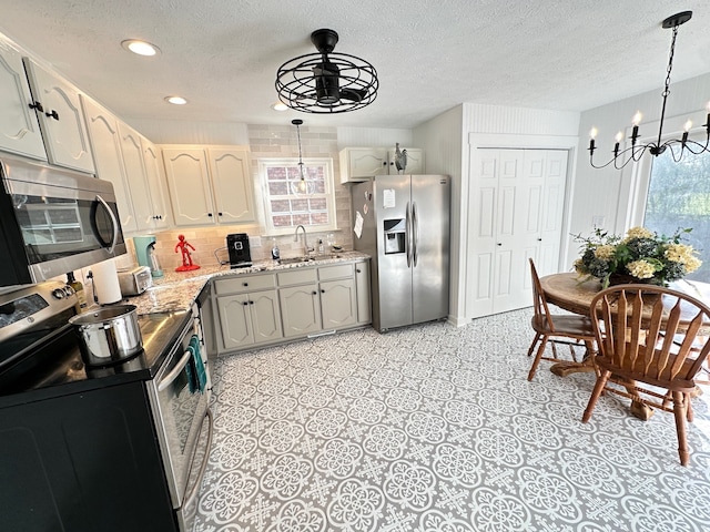 kitchen with appliances with stainless steel finishes, pendant lighting, sink, and tasteful backsplash